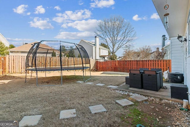 view of yard with a trampoline and a patio area