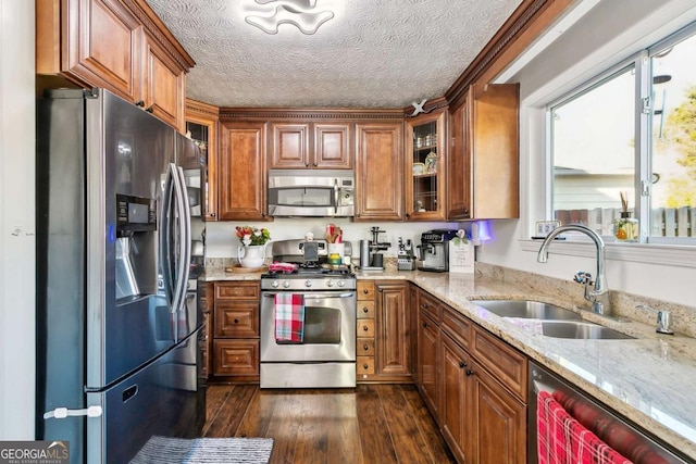 kitchen with dark wood-type flooring, sink, light stone countertops, a textured ceiling, and appliances with stainless steel finishes