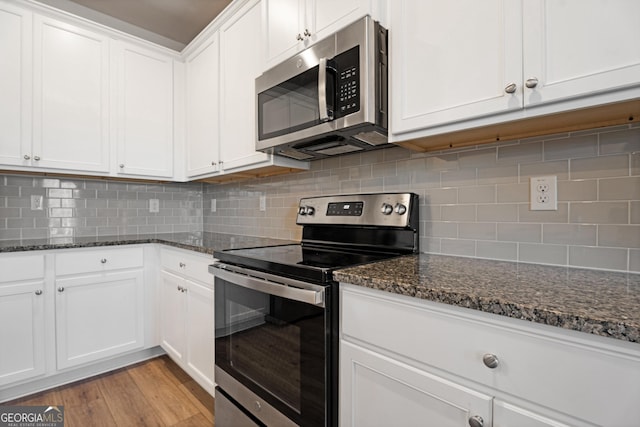 kitchen featuring white cabinets, appliances with stainless steel finishes, decorative backsplash, and dark stone counters