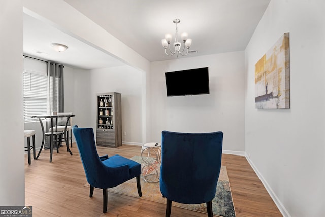 sitting room with hardwood / wood-style floors and a notable chandelier