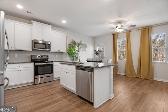 kitchen with dark stone counters, sink, white cabinets, and stainless steel appliances