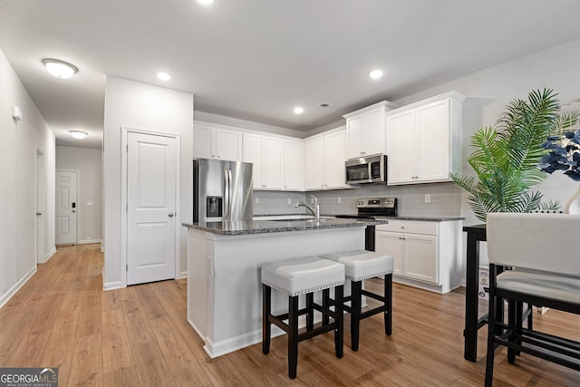 kitchen featuring white cabinets, stainless steel appliances, and a kitchen island with sink