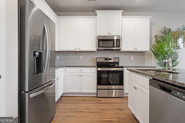 kitchen featuring dark stone countertops, white cabinets, and appliances with stainless steel finishes