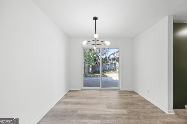 unfurnished dining area featuring light hardwood / wood-style floors and an inviting chandelier