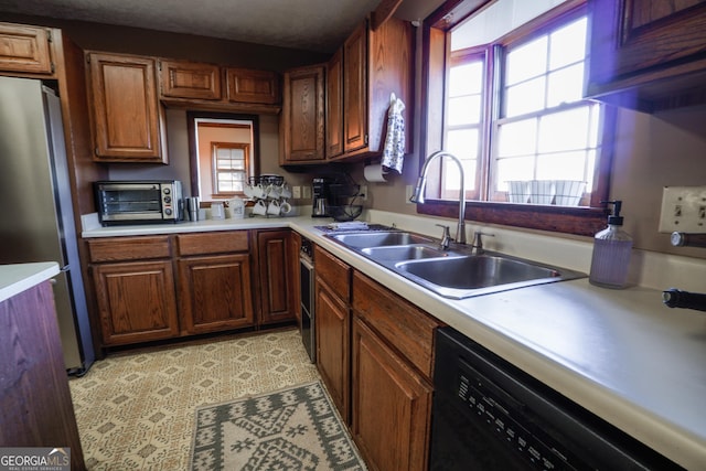 kitchen with stainless steel fridge, black dishwasher, and sink