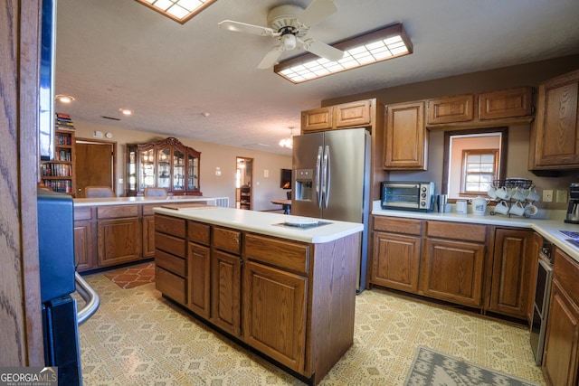 kitchen with ceiling fan, light tile patterned floors, stainless steel fridge with ice dispenser, kitchen peninsula, and a kitchen island