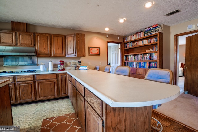 kitchen featuring a breakfast bar area, white gas stovetop, a center island, and a textured ceiling