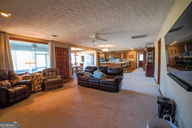 living room with ceiling fan with notable chandelier, light colored carpet, and a textured ceiling