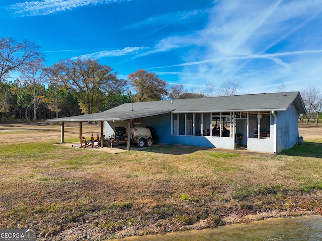 rear view of house with a lawn, a sunroom, and a carport