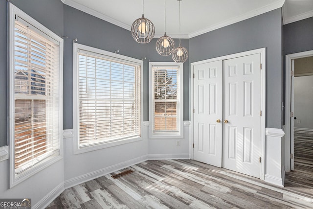 unfurnished dining area with crown molding, wood finished floors, visible vents, and a chandelier
