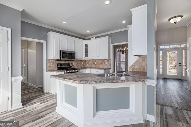 kitchen with wood finished floors, white cabinetry, stainless steel appliances, and a sink