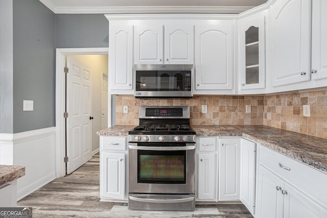 kitchen featuring white cabinetry, stainless steel appliances, light wood-type flooring, and crown molding