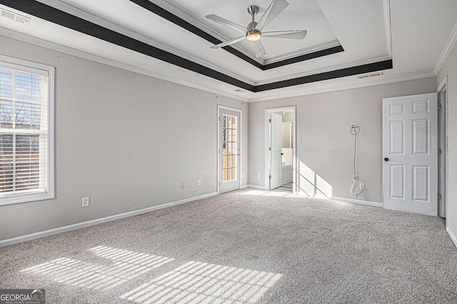 unfurnished bedroom with a tray ceiling, carpet floors, visible vents, and crown molding