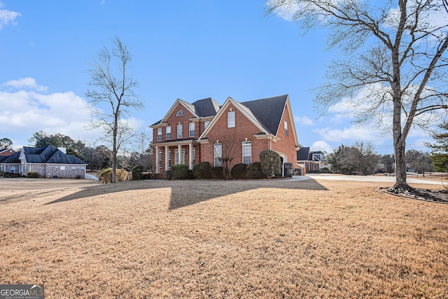 traditional-style home featuring brick siding and a front lawn