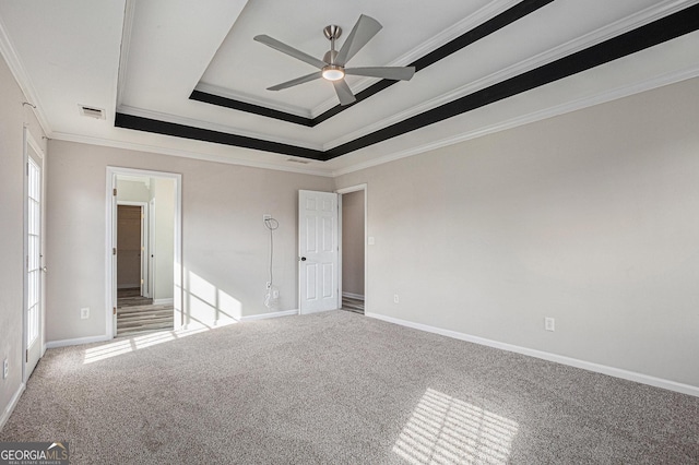 unfurnished bedroom with visible vents, baseboards, a tray ceiling, ornamental molding, and light carpet