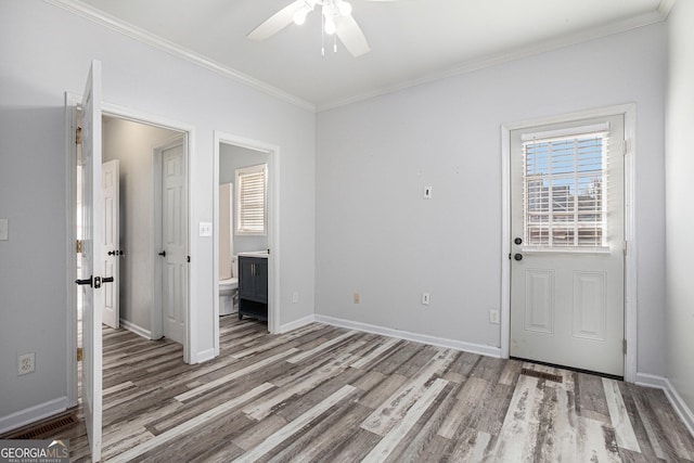 unfurnished bedroom featuring a ceiling fan, wood finished floors, connected bathroom, crown molding, and baseboards