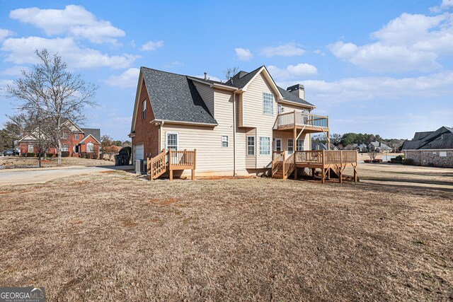 rear view of house featuring a wooden deck, concrete driveway, roof with shingles, cooling unit, and a chimney