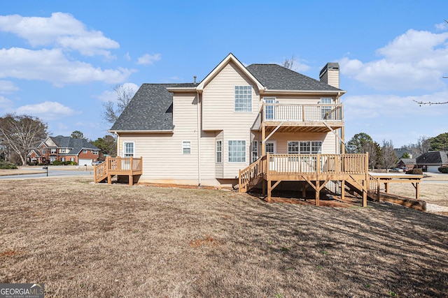 back of property with a wooden deck, a balcony, roof with shingles, and a chimney