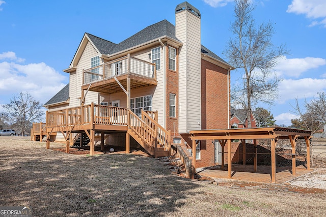 rear view of property with a chimney, roof with shingles, a balcony, stairs, and a patio area