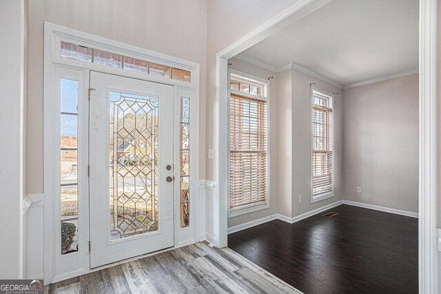foyer with visible vents, crown molding, baseboards, and wood finished floors