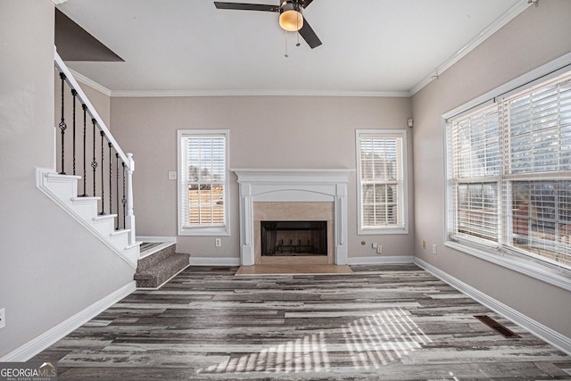 unfurnished living room featuring a wealth of natural light, crown molding, ceiling fan, and wood finished floors