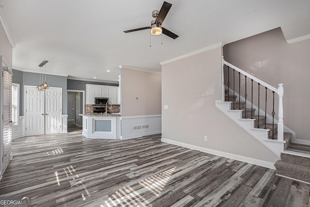 unfurnished living room with visible vents, ceiling fan, dark wood finished floors, stairway, and a sink