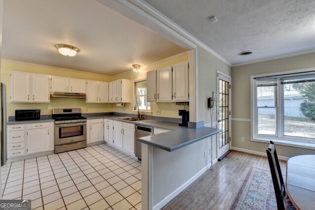 kitchen featuring white cabinets, sink, ornamental molding, a textured ceiling, and appliances with stainless steel finishes