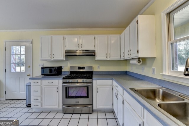 kitchen featuring gas stove, white cabinetry, a healthy amount of sunlight, and light tile patterned floors