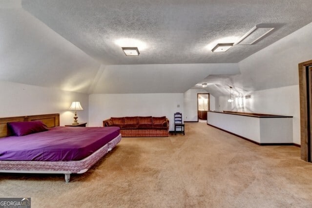 bedroom with light carpet, a textured ceiling, and lofted ceiling