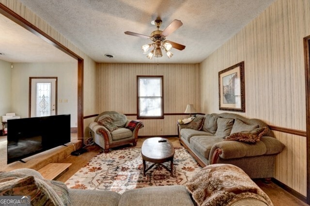 living room featuring a textured ceiling, ceiling fan, and a healthy amount of sunlight