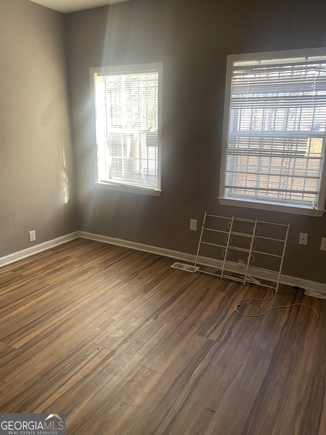 empty room with dark hardwood / wood-style floors and a healthy amount of sunlight