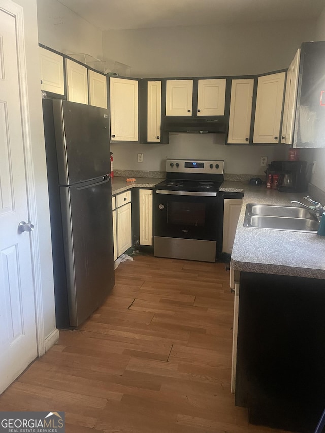 kitchen featuring wood-type flooring, appliances with stainless steel finishes, white cabinetry, and sink