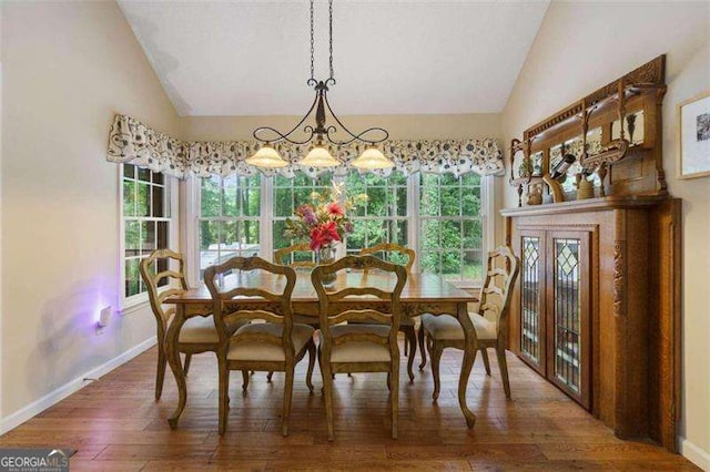 dining area featuring dark wood-type flooring and vaulted ceiling