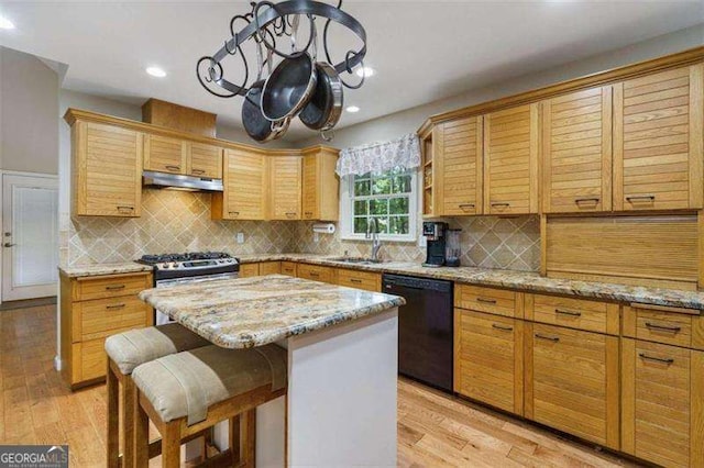 kitchen featuring dishwasher, sink, light stone counters, decorative backsplash, and a kitchen island