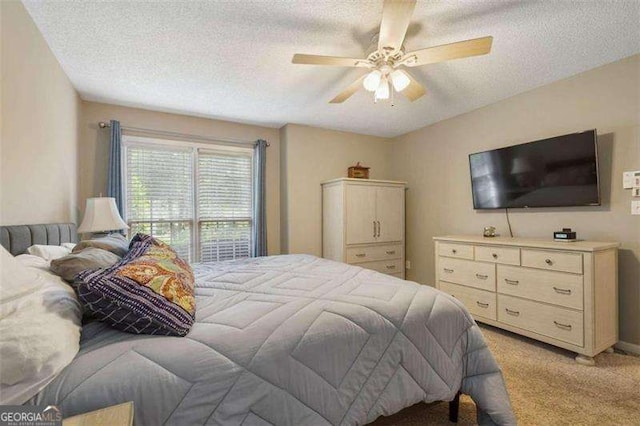 carpeted bedroom featuring ceiling fan and a textured ceiling