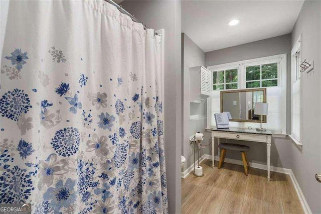 bathroom with curtained shower, hardwood / wood-style floors, and toilet