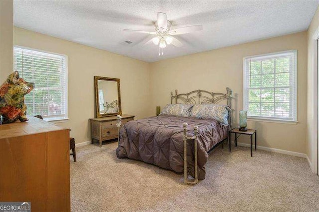 carpeted bedroom featuring ceiling fan and a textured ceiling