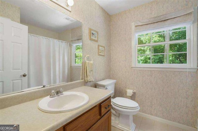 bathroom featuring tile patterned floors, vanity, a healthy amount of sunlight, and toilet