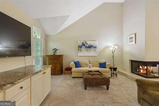 carpeted living room with a multi sided fireplace and vaulted ceiling