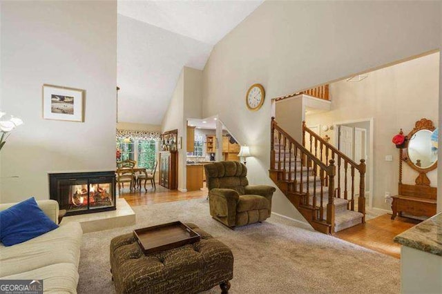 living room featuring a multi sided fireplace, light carpet, and high vaulted ceiling