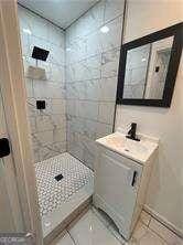 bathroom with tile patterned floors, mail boxes, sink, and tiled shower