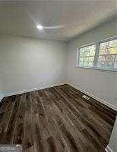 spare room with dark hardwood / wood-style flooring and plenty of natural light