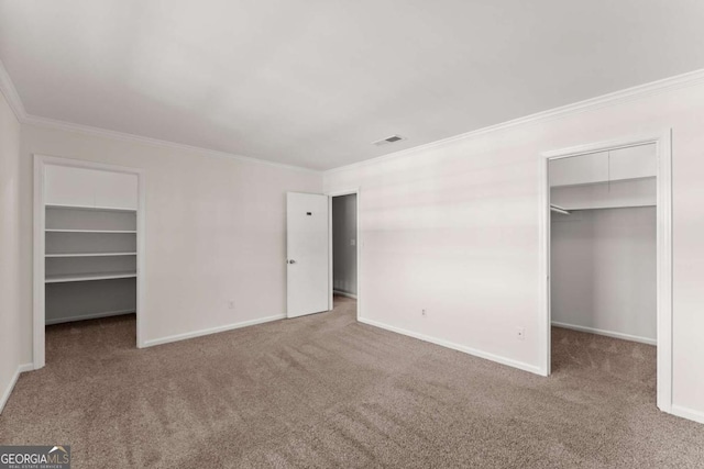 unfurnished bedroom with a walk in closet, crown molding, a closet, and carpet floors