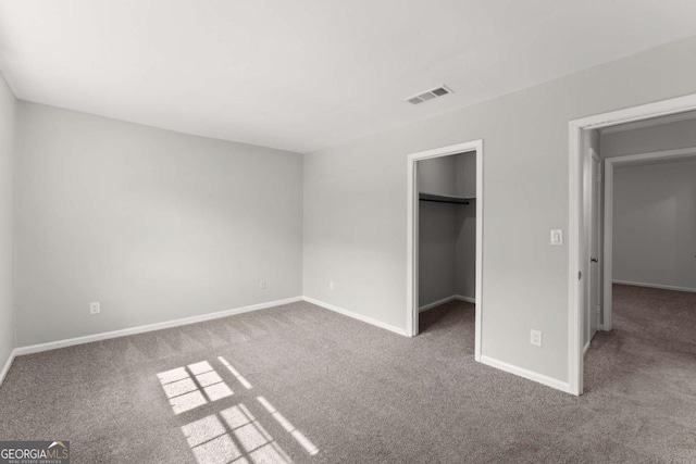 unfurnished bedroom featuring a spacious closet, a closet, and carpet