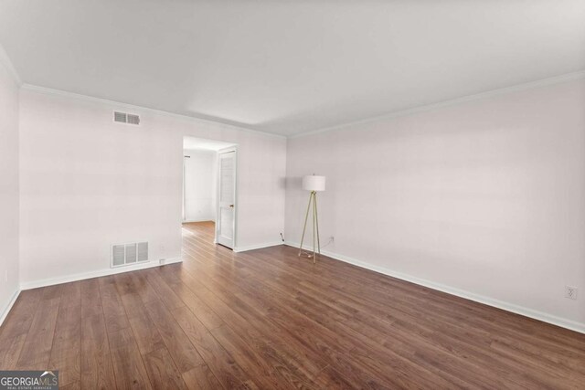 empty room featuring ornamental molding and dark wood-type flooring