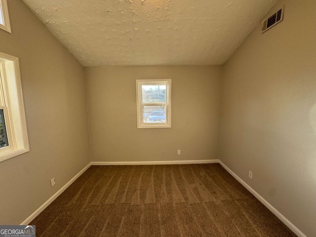 carpeted empty room with a textured ceiling