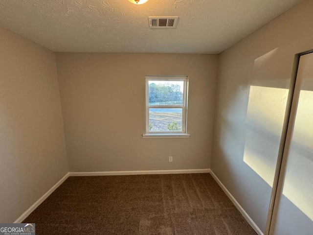 spare room featuring carpet floors and a textured ceiling