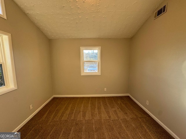 empty room with carpet floors and a textured ceiling