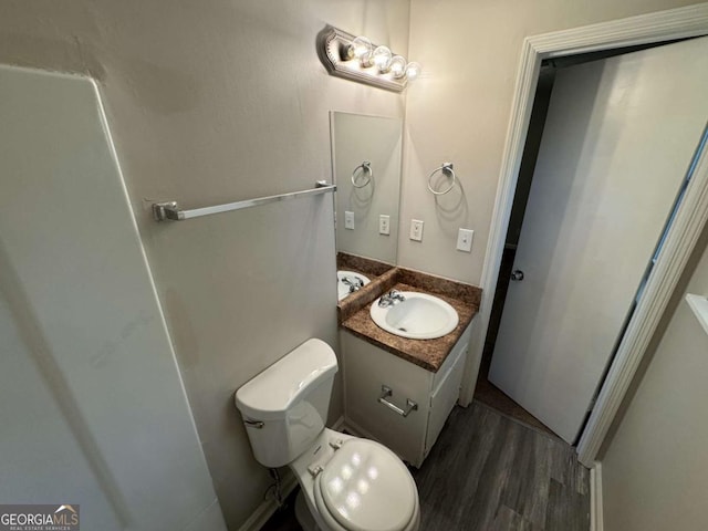 bathroom with toilet, vanity, and wood-type flooring