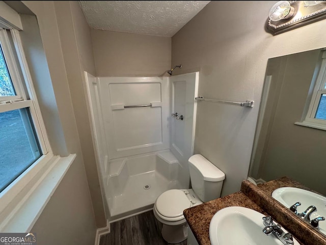 bathroom with a textured ceiling, toilet, walk in shower, and vanity